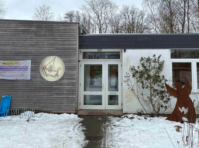 Ein einstöckiges Gebäude im Schnee. Links neben der Tür hängt ein Logo