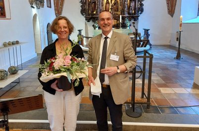 Ein Mann und eine Frau mit einem Blumenstrauß lächeln in die Kamera