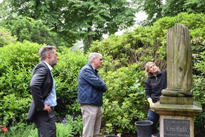 Drei Menschen im Gespräch an einem Grabmal