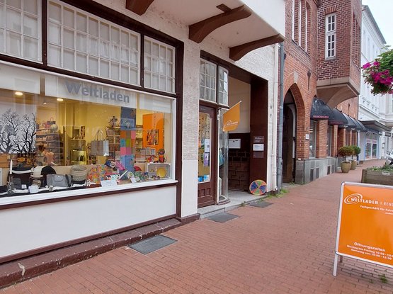 Außenansicht des Rendsburger Weltladens im Juni 2024 mit einem orangenen Schild