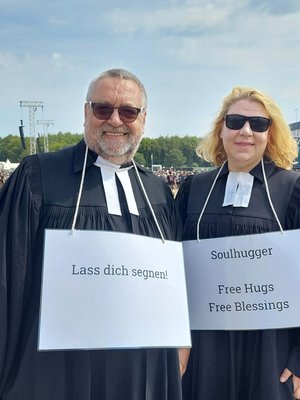 Pastorin und Pastor mit Schildern