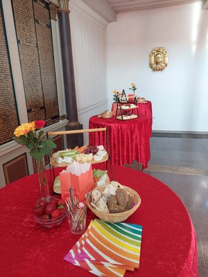 Stehtische mit roten Decken, auf denen Essen und Blumen stehen.